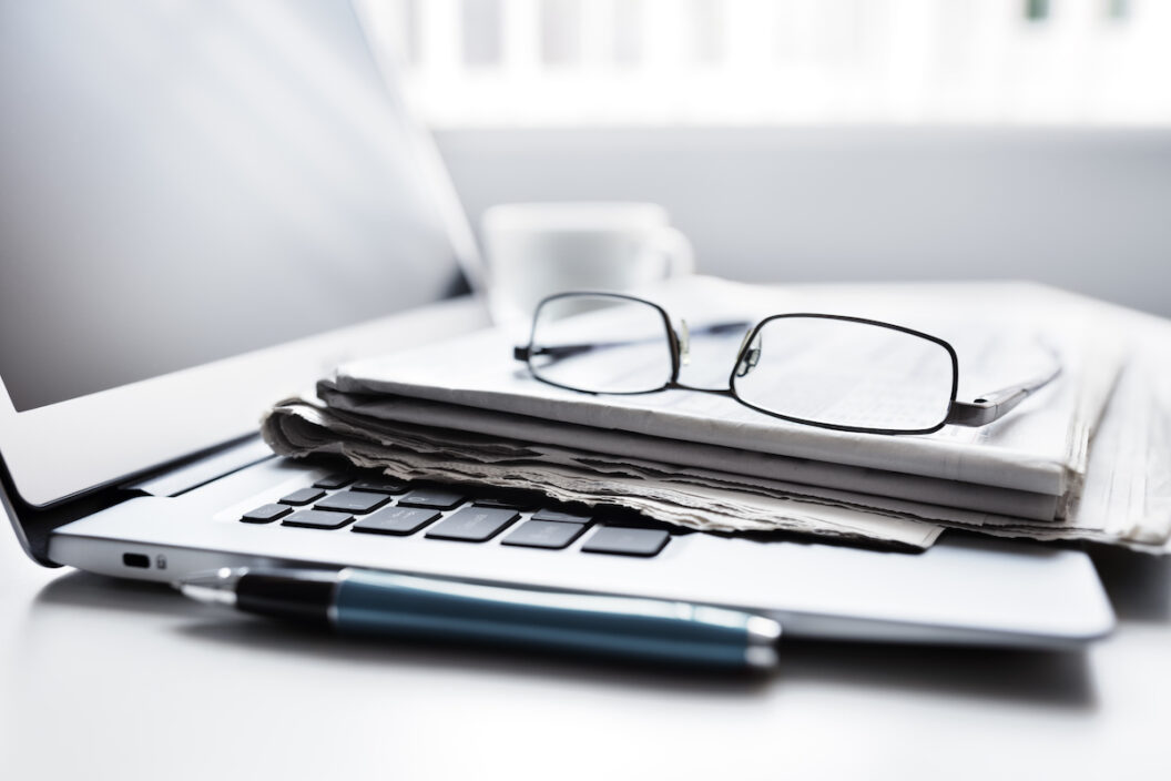 Newspaper on laptop with glasses