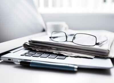 Newspaper on laptop with glasses